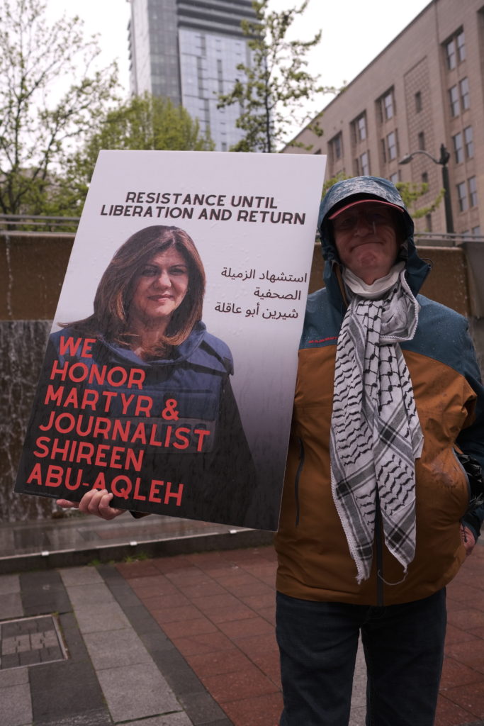 A protestor brandishes a sign depicting Aqleh.