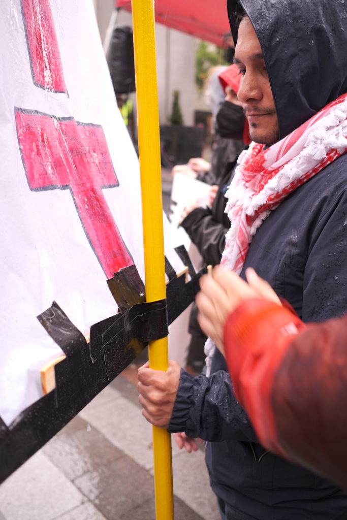Two people take shifts supporting banners calling for “BDS” or ‘Boycott, Divestment, and Sactions’, a Palestinian-led movement for freedom.